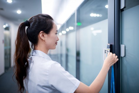 A business woman is using card open the electronic door of office