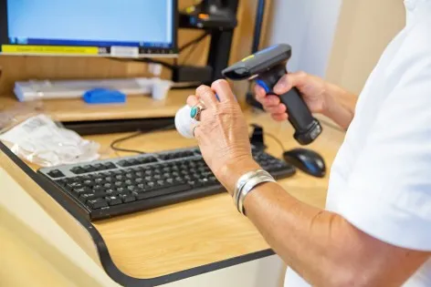 A nurse is preparing medicine for a patient. She uses the computer in the room to log in and check all the information for the patient. RM