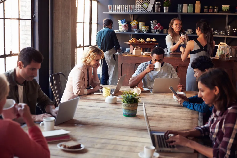 Interior Of Coffee Shop With Customers Using Digital Devices