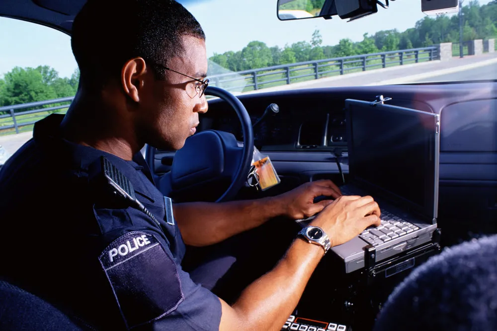 Policeman working on computer in car