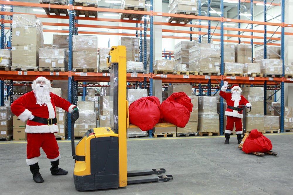 two santa clauses workers at work in large storehouse