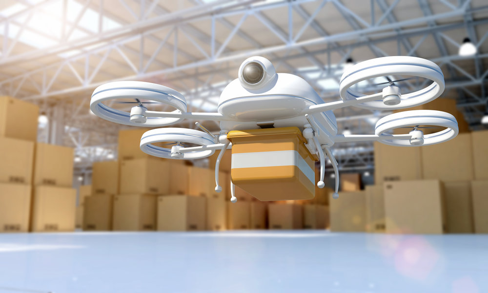 Composite image of a 3D generated model of a remote controlled drone taking off from a distribution warehouse full of cardboard boxes and goods. Drone is carrying a package for remote delivery: technology innovations allow quick shipping and delivery. The quadricopter has a camera and GPS to follow the route to destination. Drone model is white, carrying a brown yellow box.