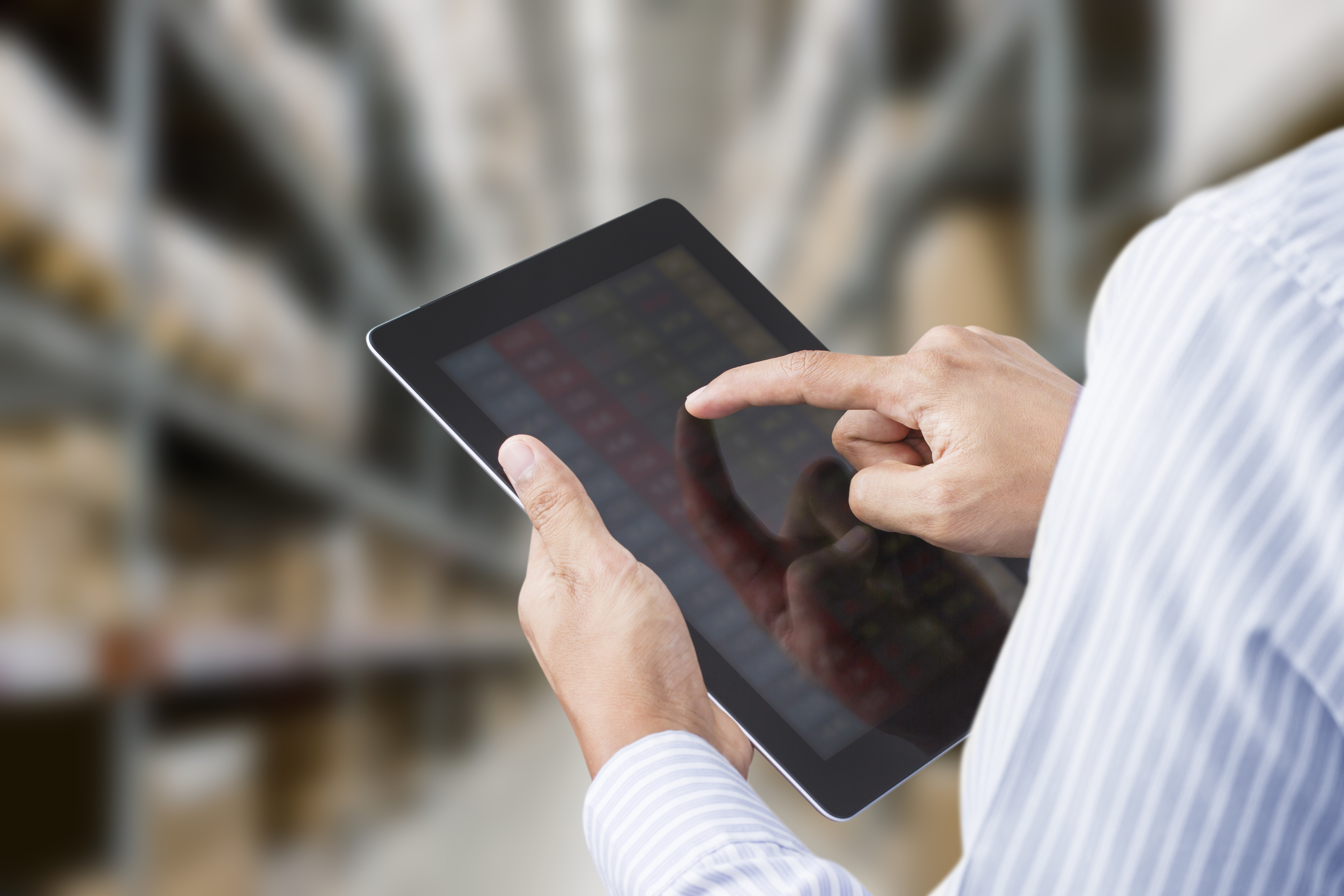 Businessman checking inventory in stock room of a manufacturing company on touchscreen tablet