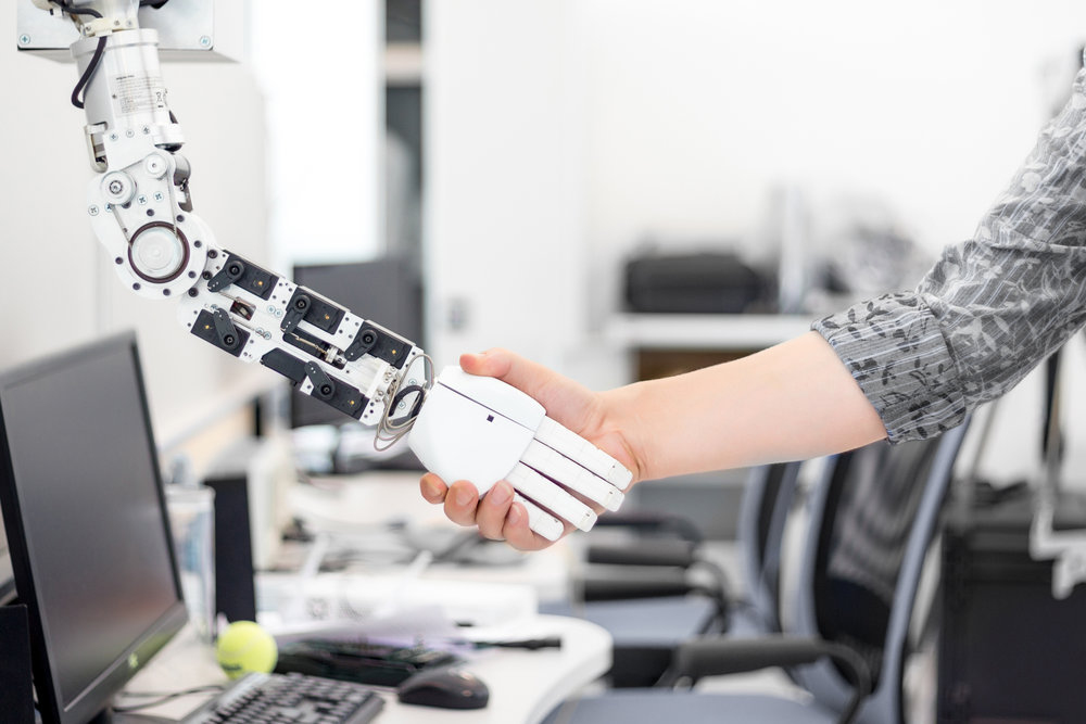 mechanized robot hand holds the objects drawn to a man's hand shaking hands