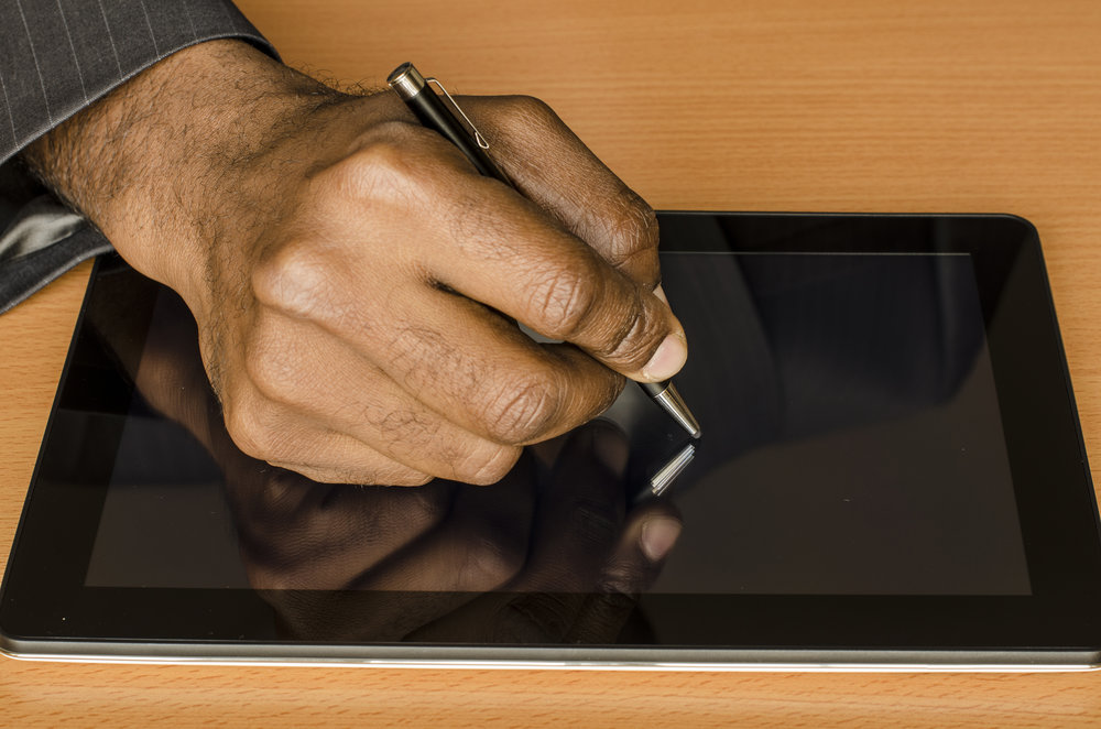 hand of a black man writing on an electronic tablet