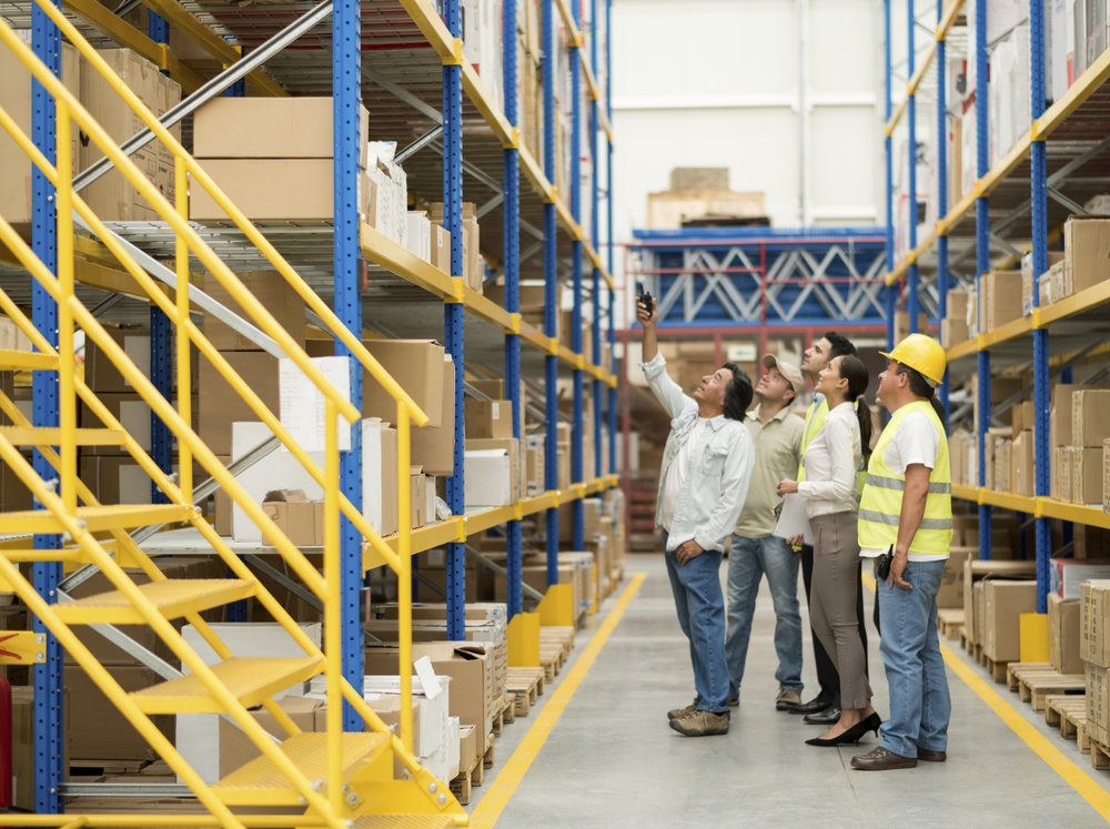 Group of people working at a warehouse and pointing at some boxes - freight transportation