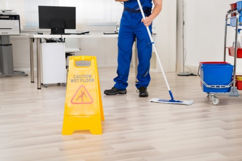 Low section of male janitor cleaning floor with mop in office