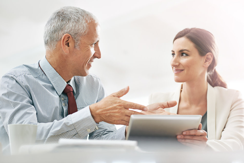 Shot of two coworkers sitting at a table using a digital tablet