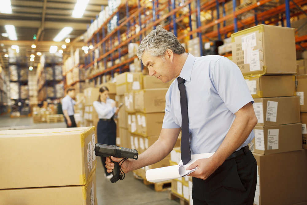 Businessman scanning shipping box in warehouse