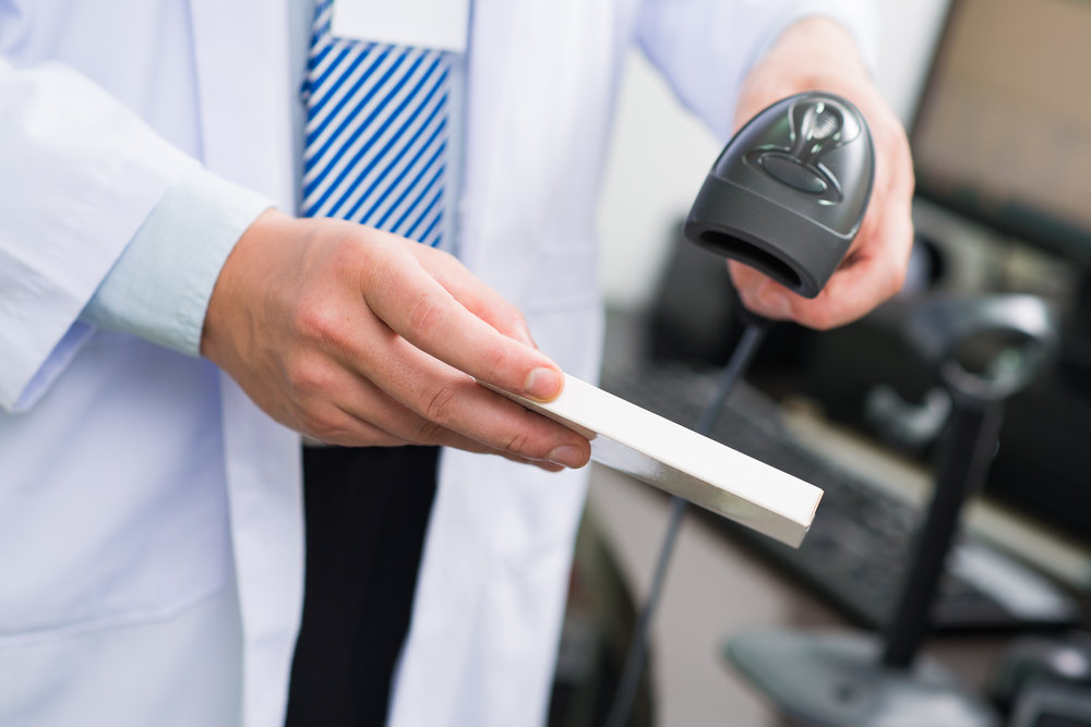 Cropped image of a pharmacist scanning bar code on the foreground