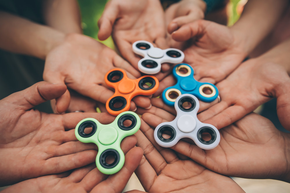 Close up of hands holding fidget spinners.