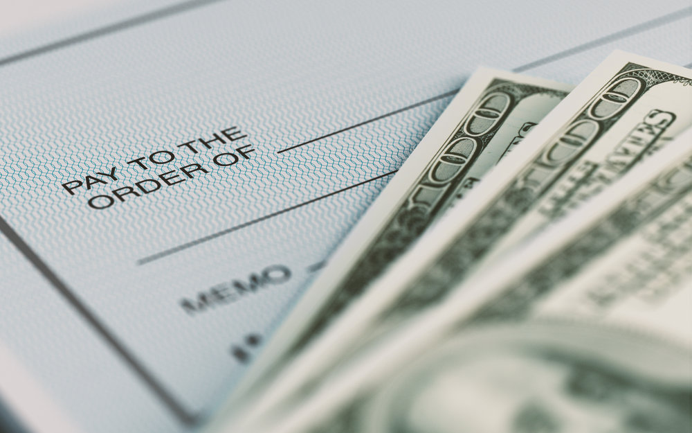 Close-up picture of a personal check and American Dollars with selective focus. Great use for financial concepts.