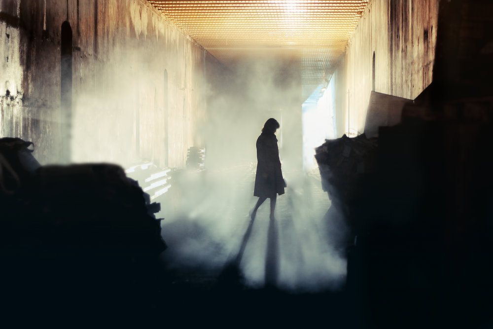 A lone wonan stands in a misty underground tunnel