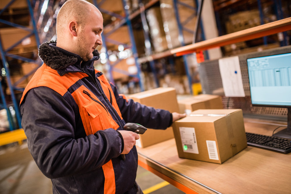Male worker scanning barcode in warehouse.